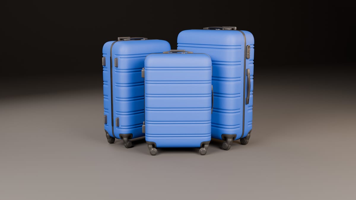 Three hard-shell suitcases in cerulean blue with a ribbed shell and a subtle orange-peel finish, dark grey corner guards, handles and spinner wheels, arranged on a dark studio backdrop.